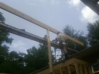 Carpenter setting a ridge beam over a new addition frame — Ice Dam Removal by Roofing Brothers in Bankston