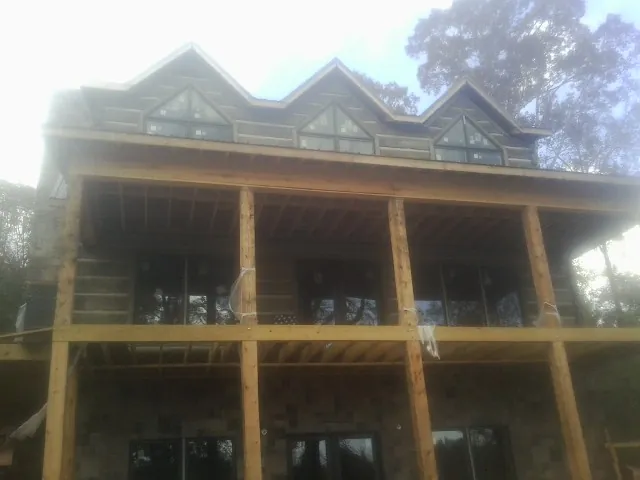 Dormers and porch framing on a large log home under construction — Roof Coating work by our crew in Bankston