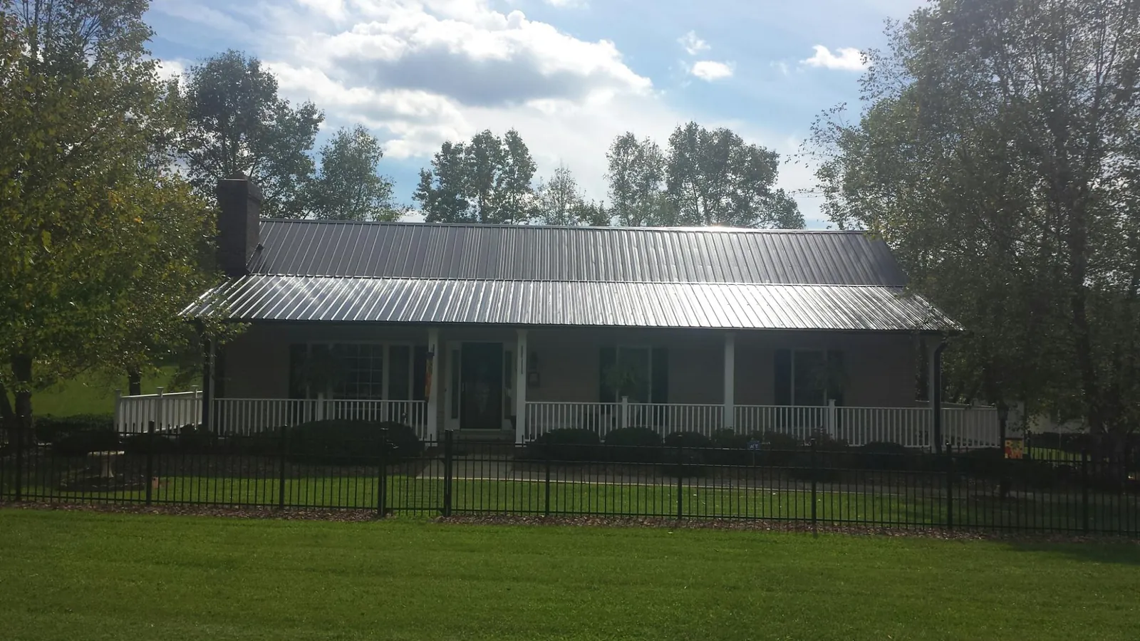Gray metal roof on a brick ranch with a full width front porch — Gutter Guard Installation work by our crew in Bankston