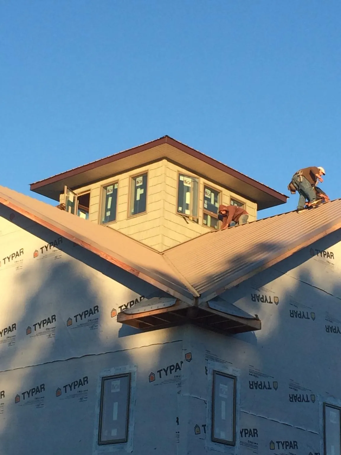 Roofers working around a rooftop cupola on a new metal roof at sunset — Roof Waterproofing in Bankston by Roofing Brothers
